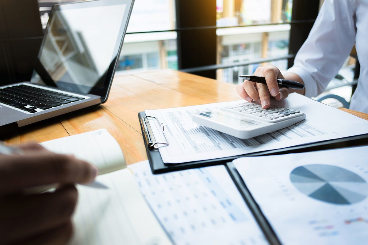 Two men calculating financial data at a desk